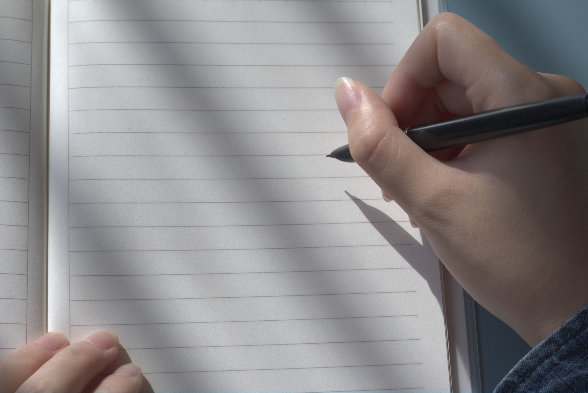 Closeup of woman's hand holding pen on open blank notebook